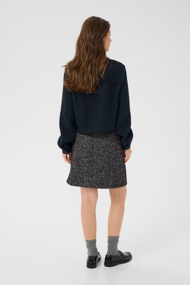 Veste décontractée à col chemise sur modèle, portée avec une jupe courte à motifs, vue de dos.