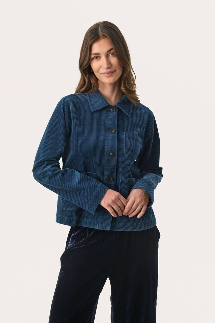 Veste en corduroy bleue avec boutons contrastants, manches longues et coupe droite, ajoutant élégance à une tenue décontractée.