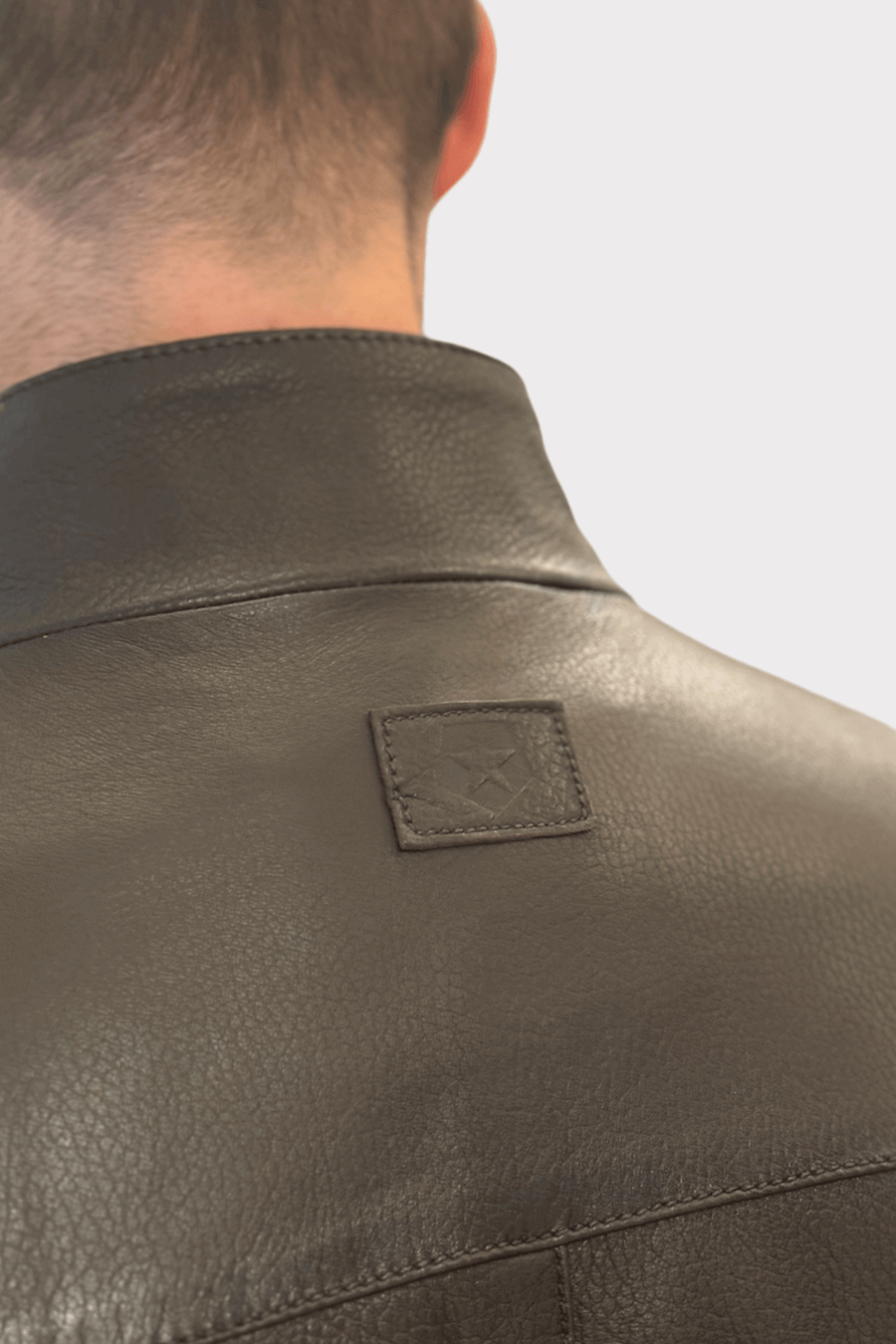 Détail du col d'une veste en cuir véritable pour homme avec une finition lisse et texturée.