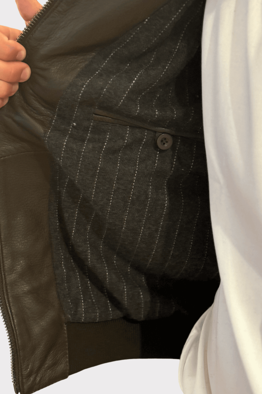 Détail de l'intérieur d'une veste en cuir, montrant une doublure texturée avec une poche.