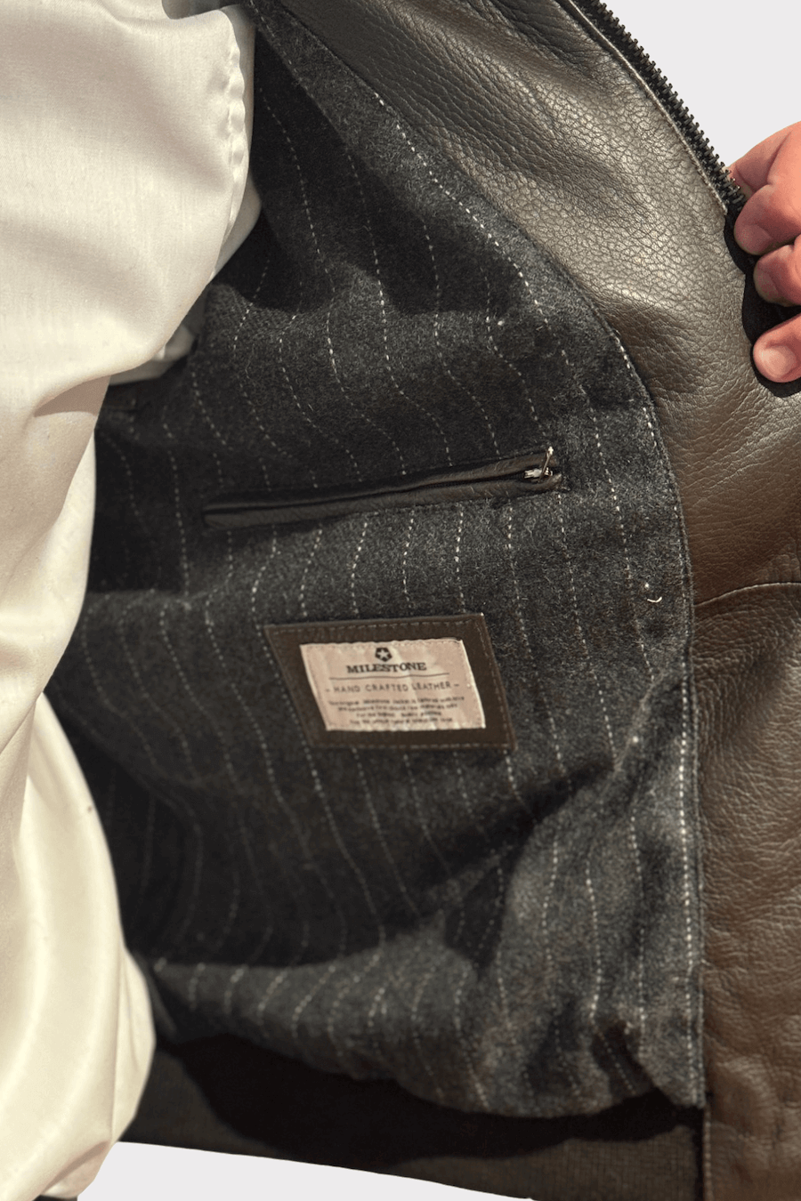 Intérieur d'une veste en cuir avec doublure texturée et poche zippée.