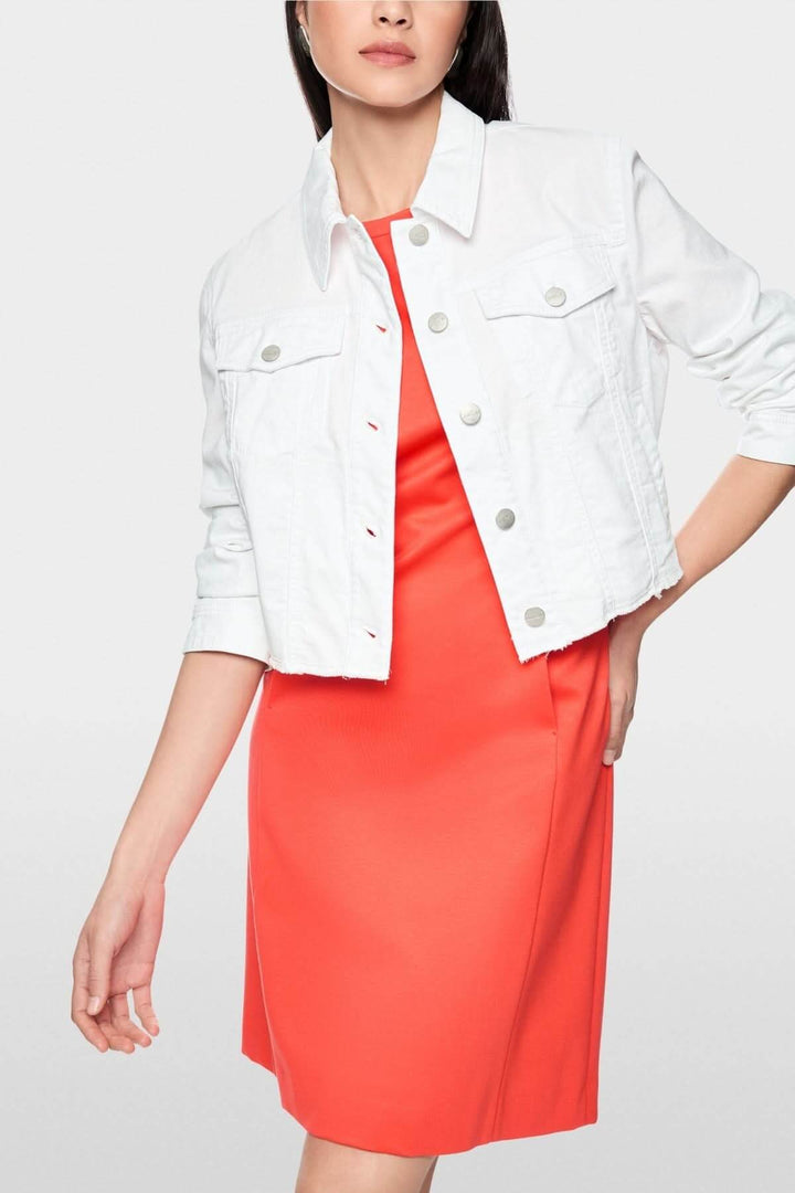 Veste en denim écourtée blanche portée sur une robe rouge, col classique, manches longues, parfait pour un look moderne et structuré.