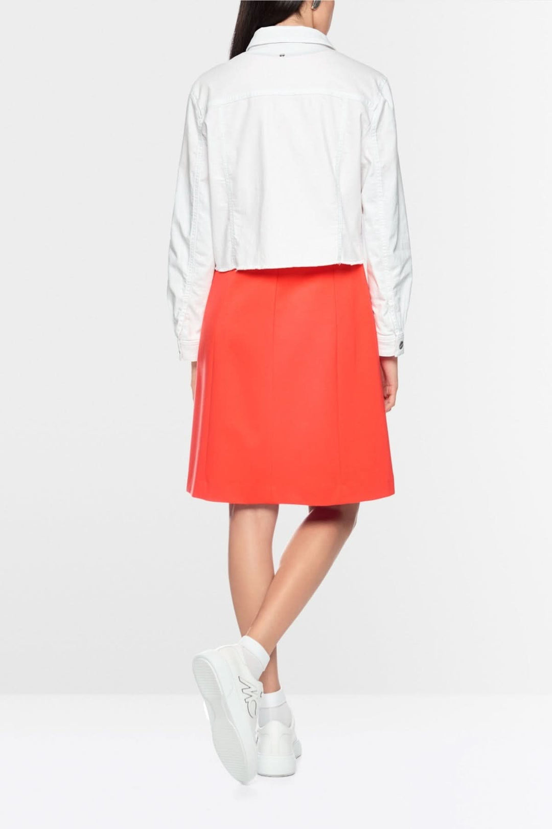 Vue arrière de la veste en denim écourtée blanche portée avec une jupe rouge, mettant en valeur sa coupe moderne et structurée.