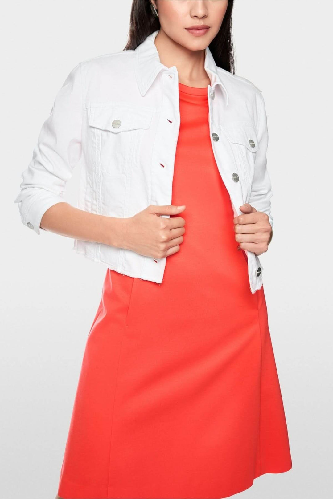 Femme portant une veste en denim écourtée blanche avec une robe orange, style moderne et structuré.