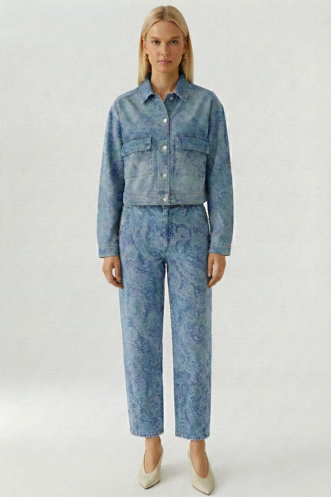 Modèle portant une veste en jean imprimée avec un motif cachemire, coupe courte et structurée, associé à un pantalon coordonné.