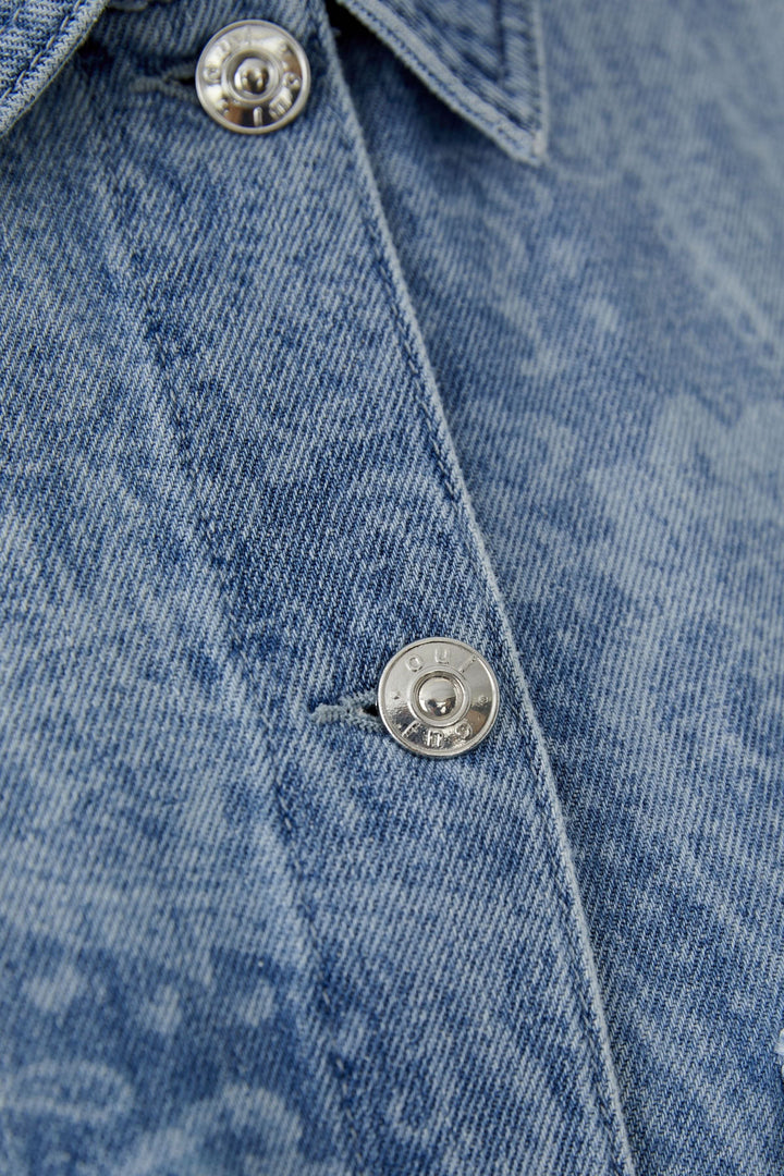 Veste en jean imprimée avec motif cachemire, col classique et fermeture boutonnée, détail de texture denim.
