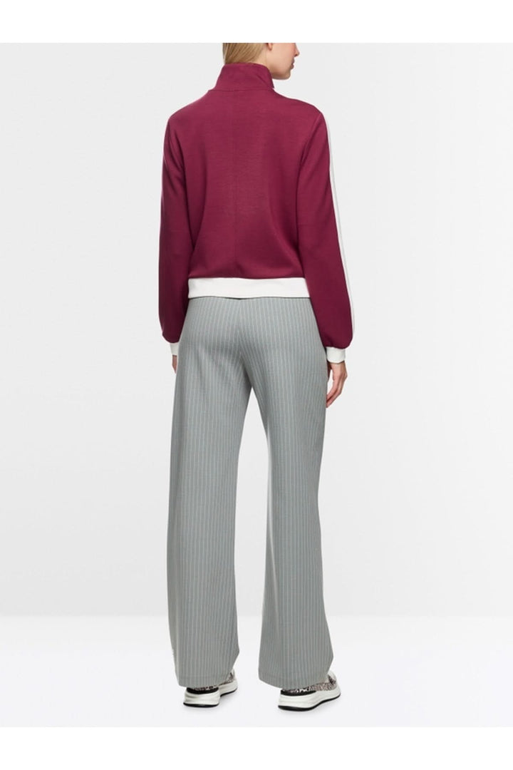 Veste en jersey ample rouge avec col montant, vue de dos, montrant les poignets et l'absence de doublure.