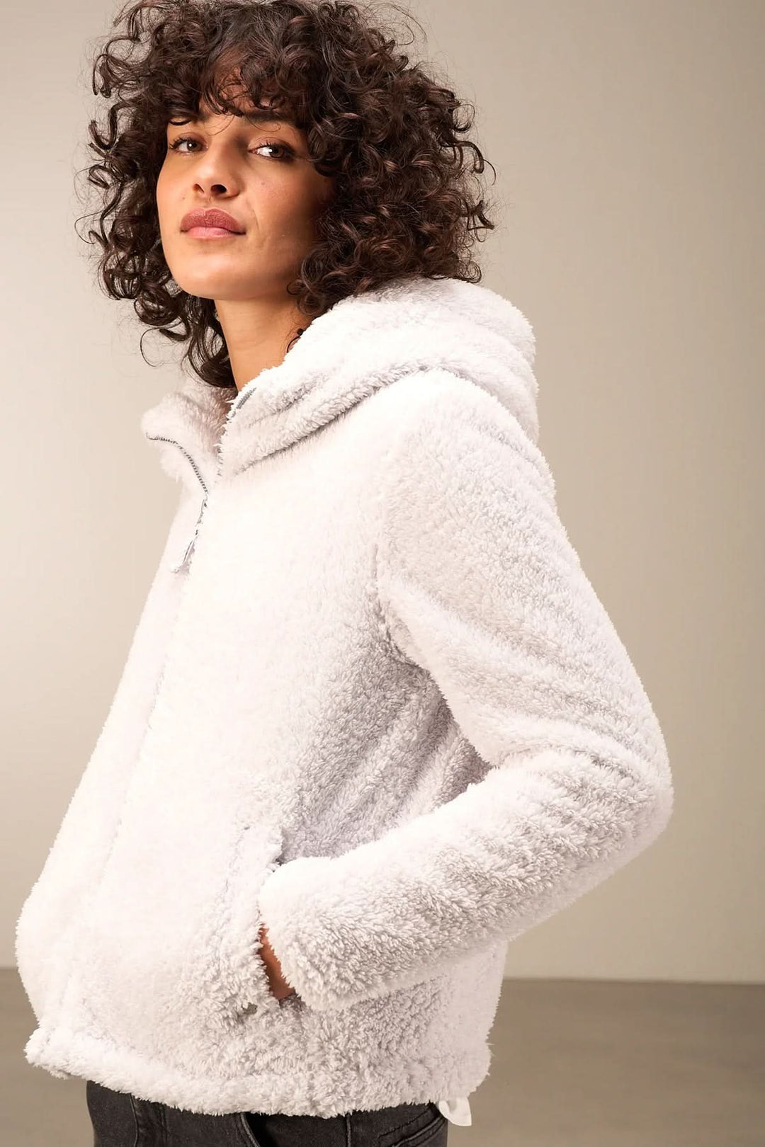 Veste en sherpa blanche avec capuche, idéale pour un style cosy-chic, vue portée par un mannequin.