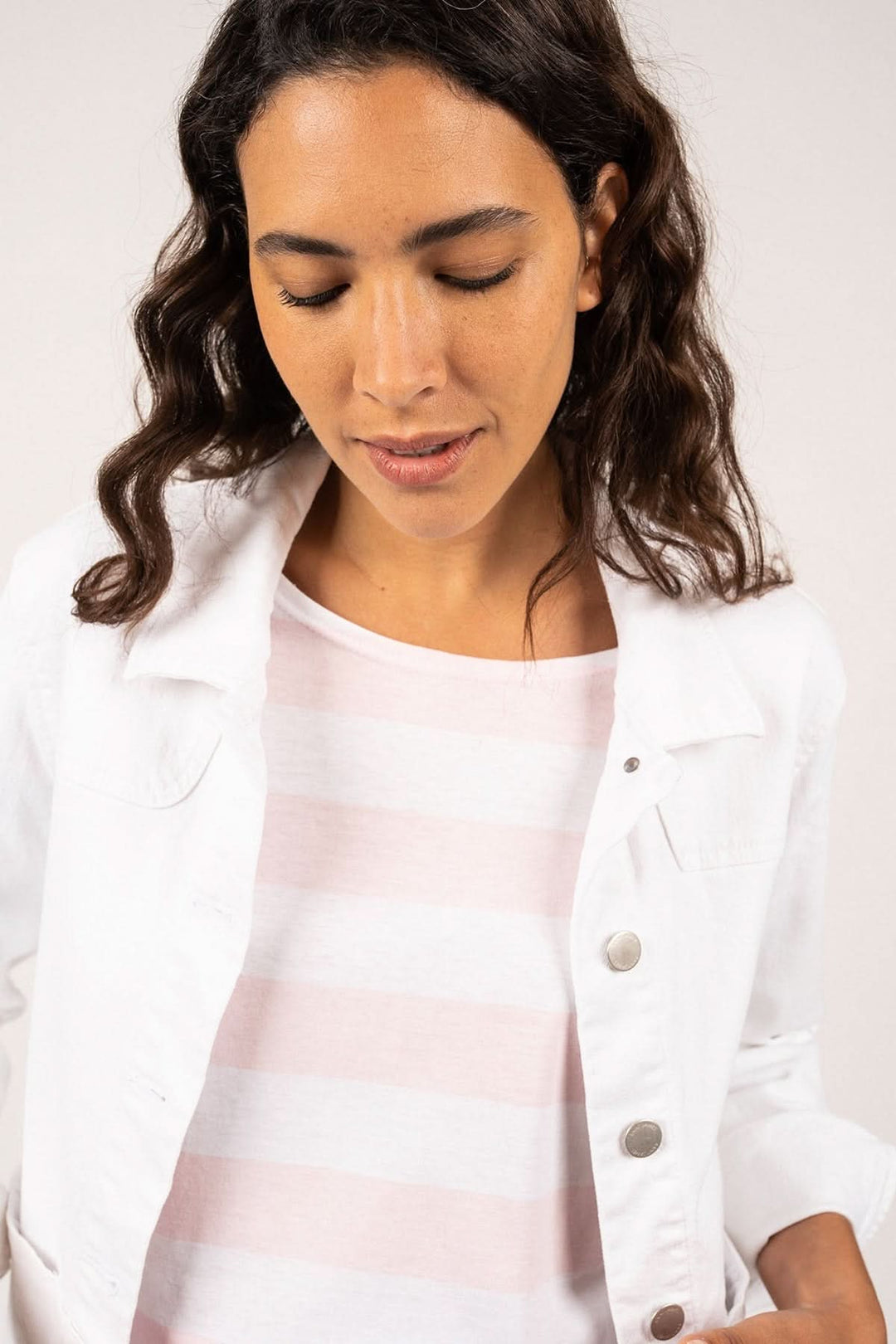 Femme portant la Veste en toile de coton STE TEA blanche avec coupe flatteuse et silhouette féminine, inspirée des vêtements de travail pratiques.