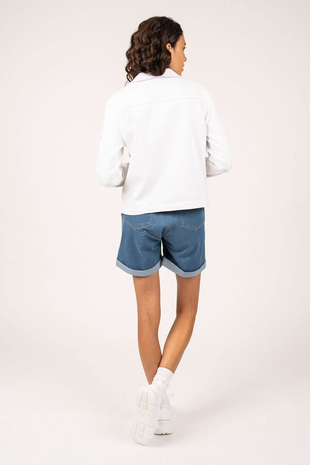 Person wearing Veste en toile de coton STE TEA, showcasing back design with denim shorts and white sneakers.