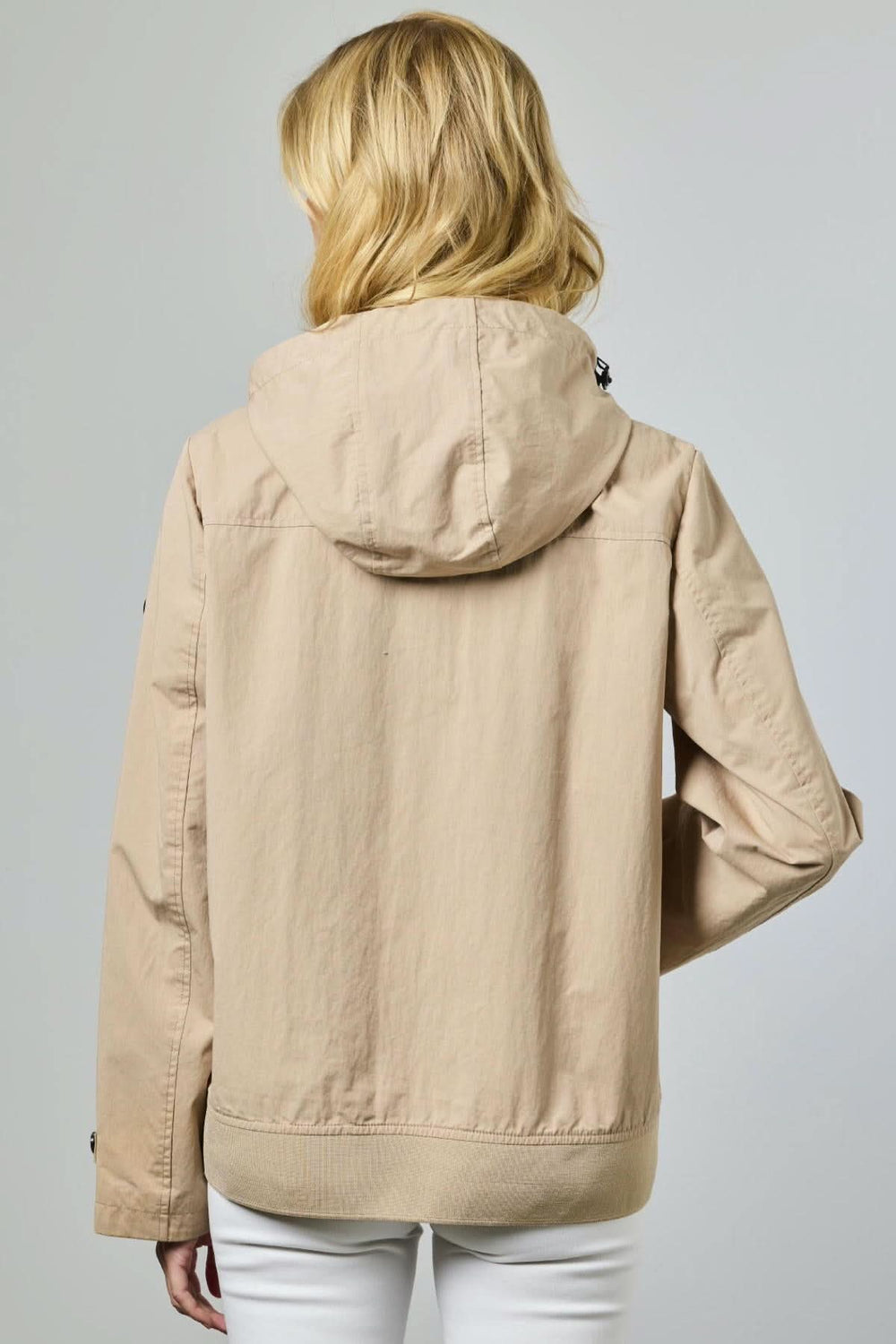 Femme portant une veste légère à capuche utilitaire beige, vue de dos, idéale pour la mi-saison avec design épuré et moderne.