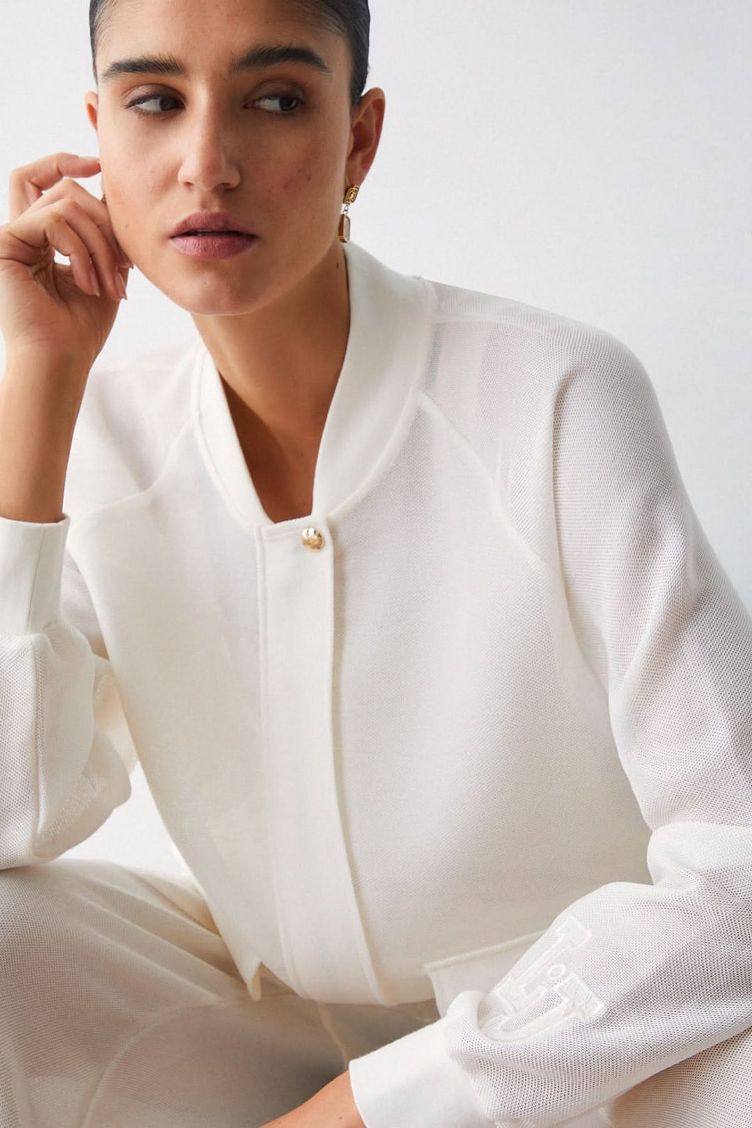 Veste légère à manches longues avec poches cargo style utilitaire, col bomber blanc, femme assise. Mode décontractée et moderne.