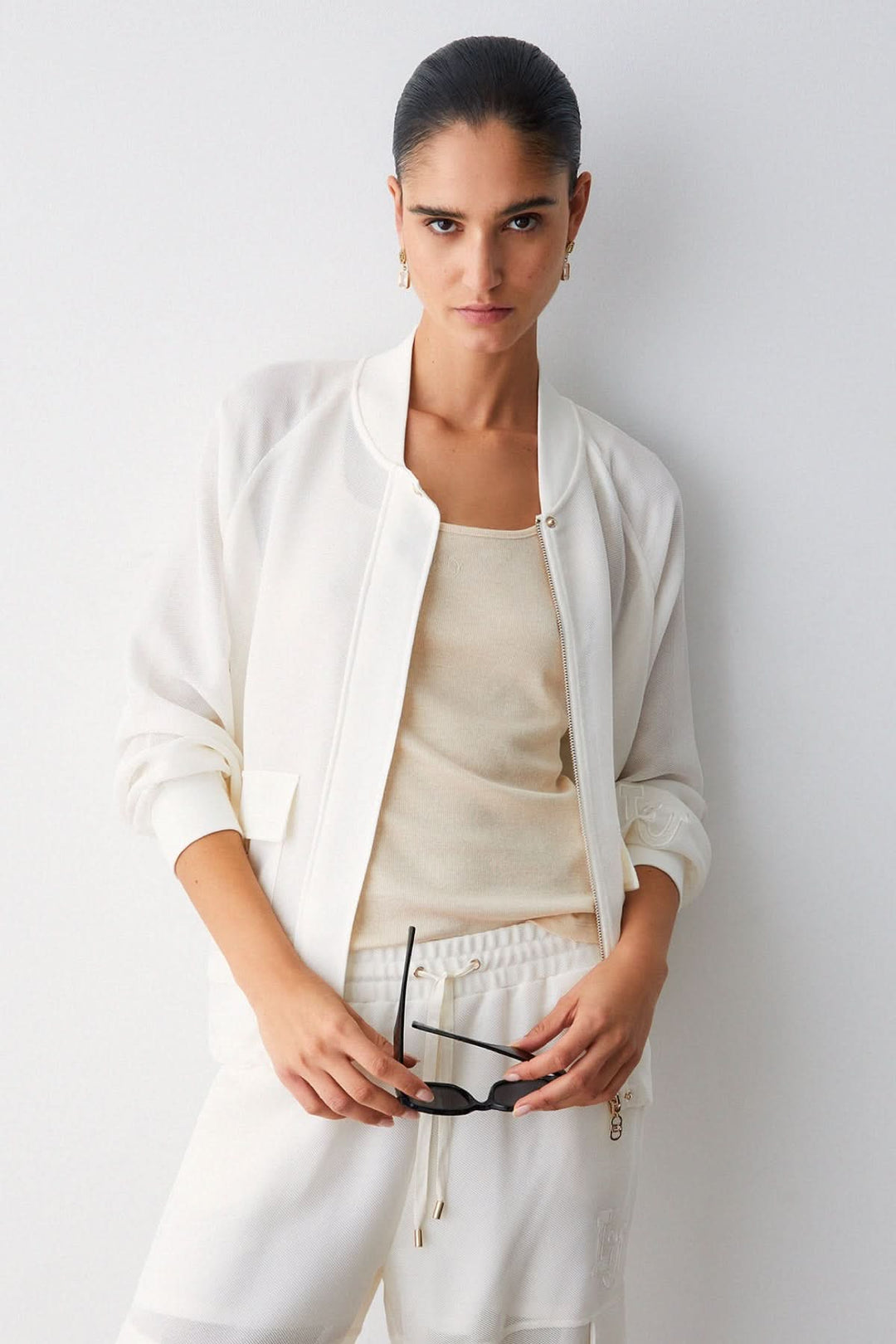 Veste légère à manches longues avec poches cargo, style utilitaire, col rond bomber, sur modèle féminin moderne élégante.