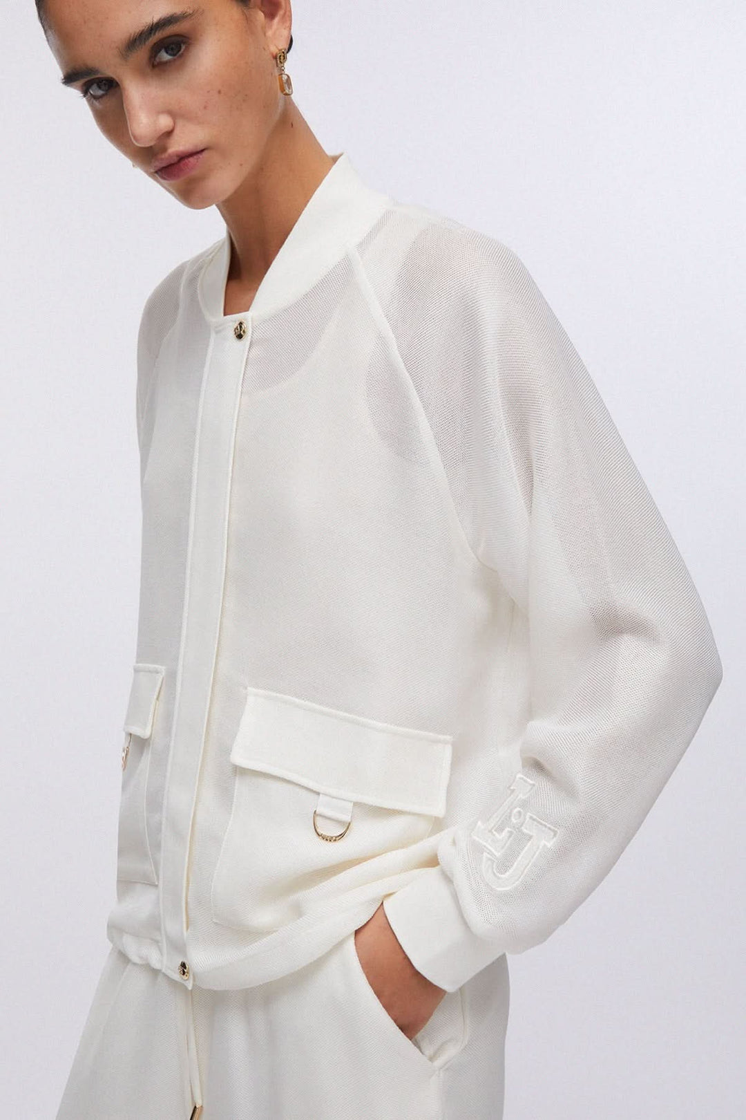 Veste légère à manches longues avec poches cargo blanche portée par une personne, élégante et moderne.