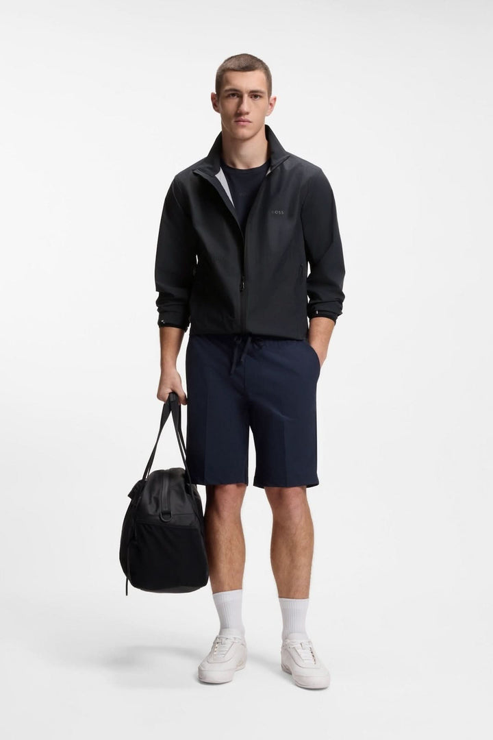 Homme portant une veste légère zippée à col montant, tenue décontractée, tenue sportive, avec un sac à la main, sur fond blanc.