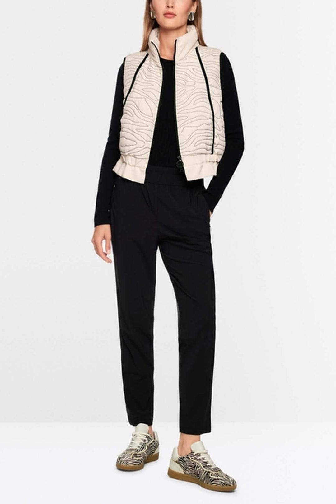 Veste matelassée avec surpiqûres ondulées, col montant et ceinture élastique, portée sur mannequin femme.