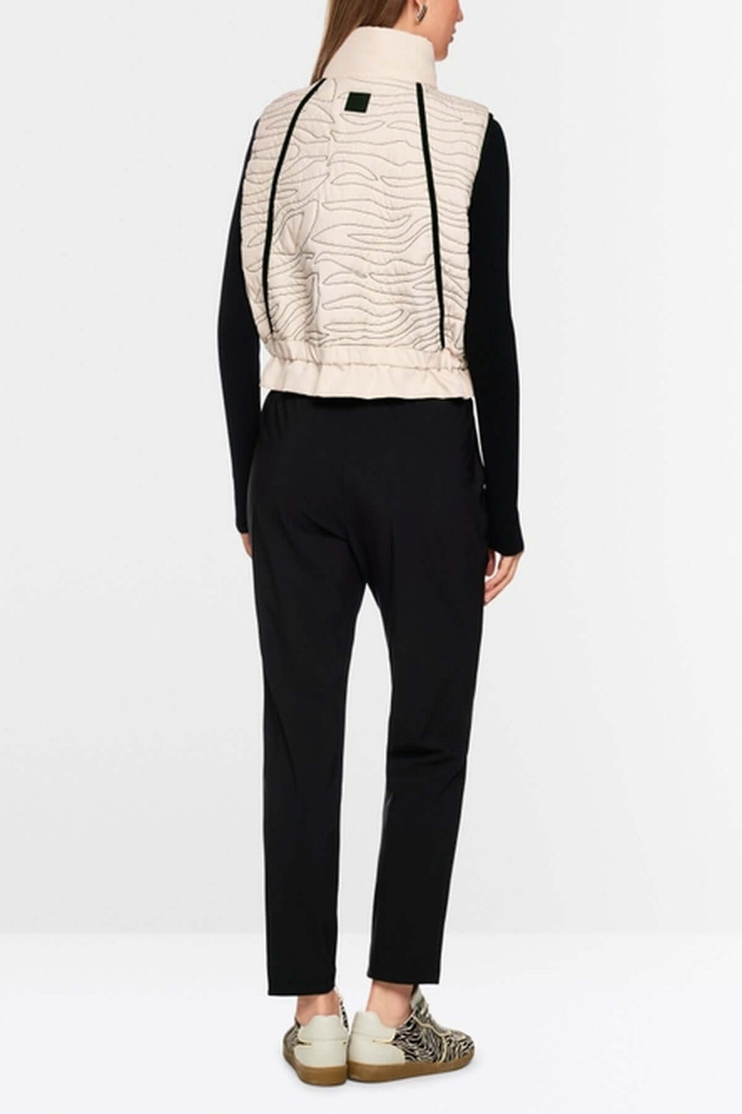 Veste matelassée beige avec surpiqûres ondulées et col montant, vue de dos. Détail sur coupe ample et ceinture élastique.