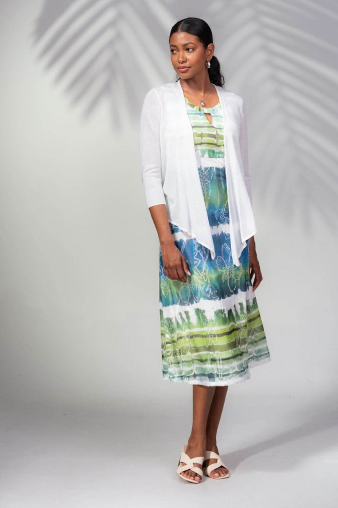 Femme portant une veste ouverte blanche sur une robe colorée, idéale pour une soirée estivale ou la mi-saison.