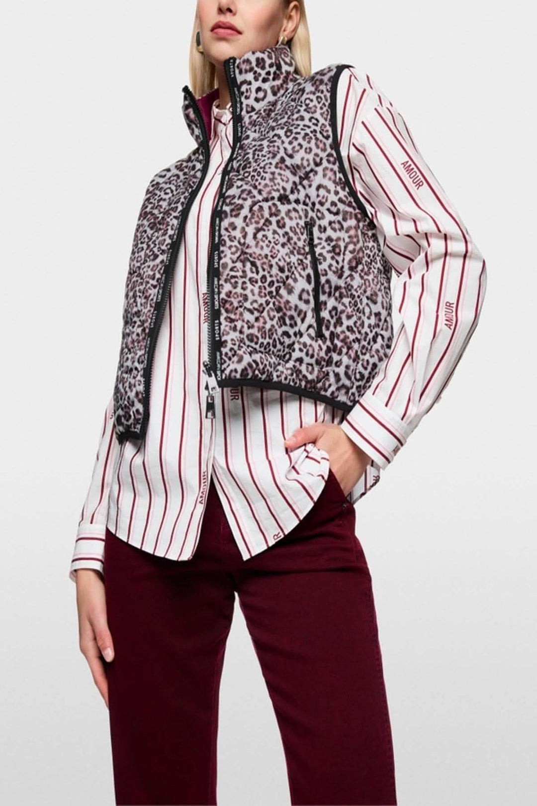 Veste sans manche réversible avec imprimé léopard porté sur chemise rayée et pantalon bordeaux, style moderne et polyvalent.