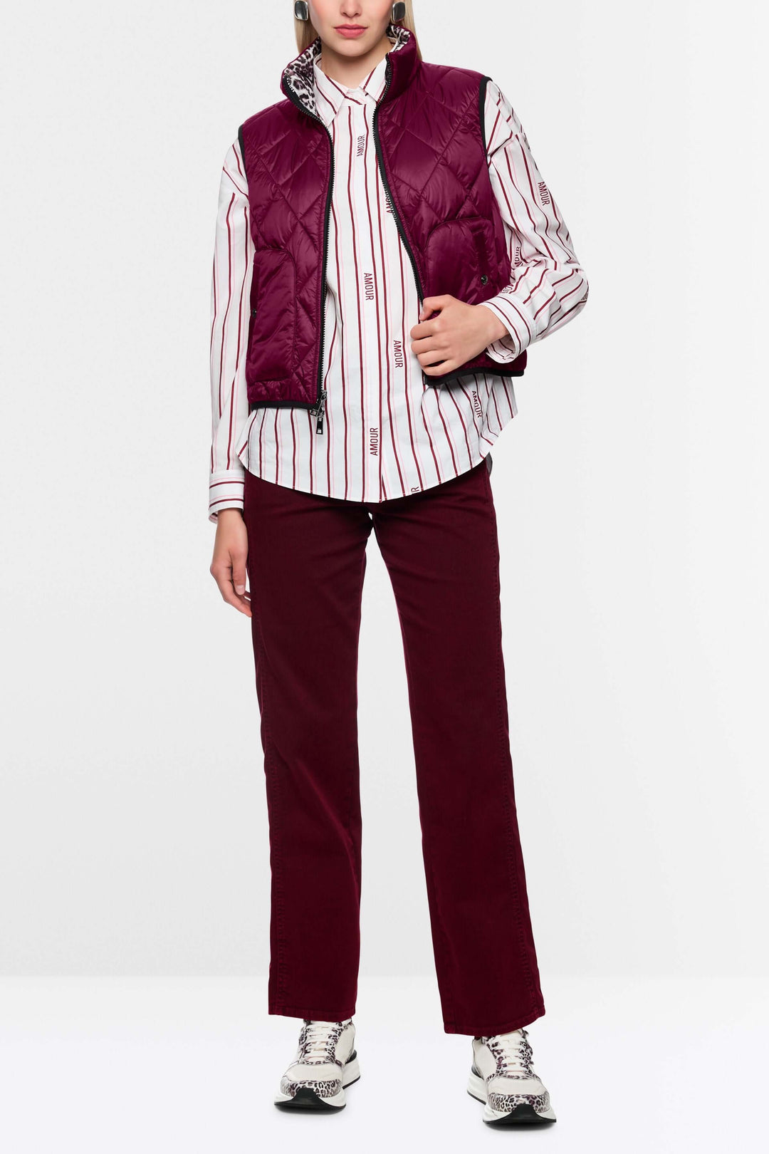 Femme portant une veste sans manche réversible avec col montant rouge et chemise rayée, idéale pour un style versatile et élégant.