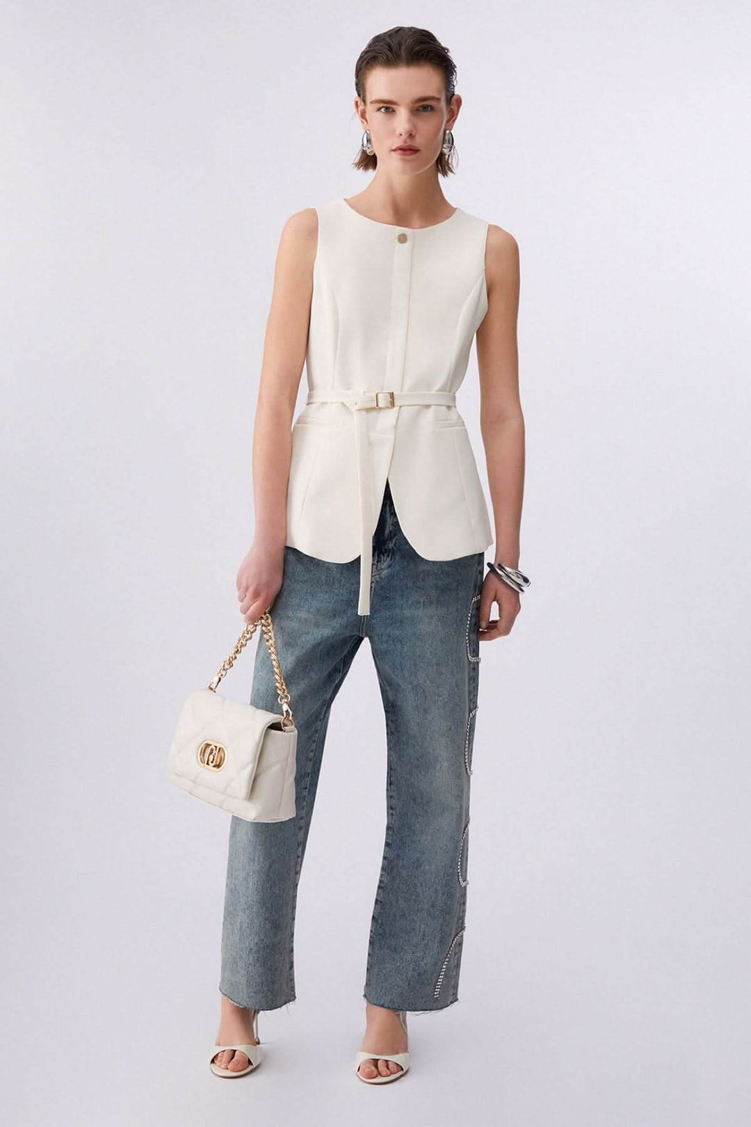 Femme portant une veste sans manches avec ceinture, silhouette élégante et moderne