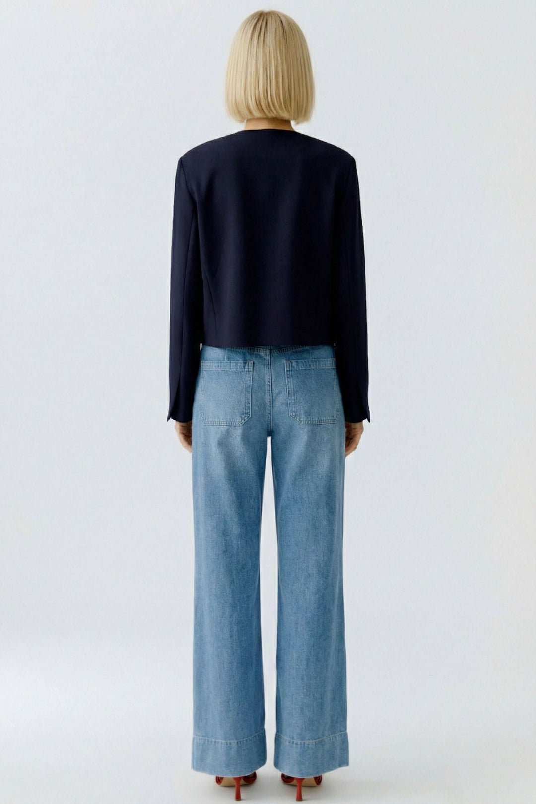 Vue arrière de la veste structurée à boutons décoratifs portée avec un jean, montrant sa coupe sophistiquée et élégante.