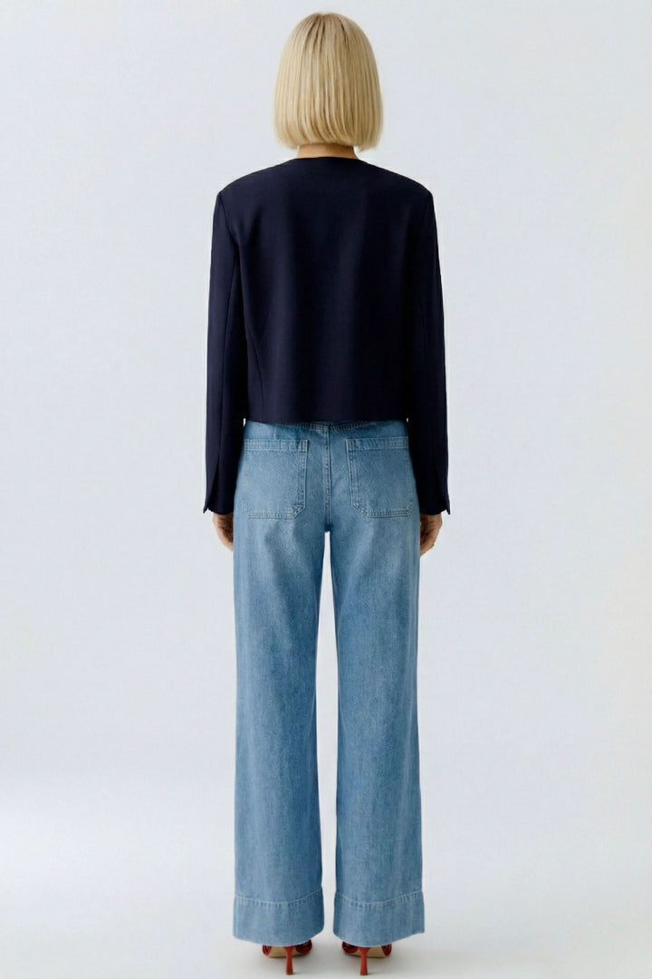 Vue arrière de la veste structurée à boutons décoratifs portée avec un jean, montrant sa coupe sophistiquée et élégante.