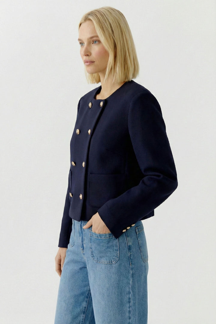 Femme portant une "Veste structurée à boutons décoratifs" avec jean pour un look chic et sophistiqué.