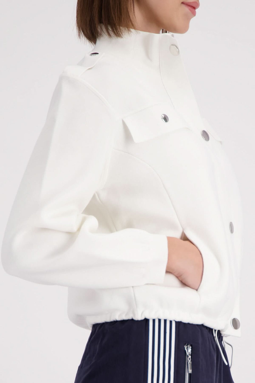 Veste structurée à col montant en blanc portée par une femme, élégante et contemporaine, idéale pour un style polyvalent.
