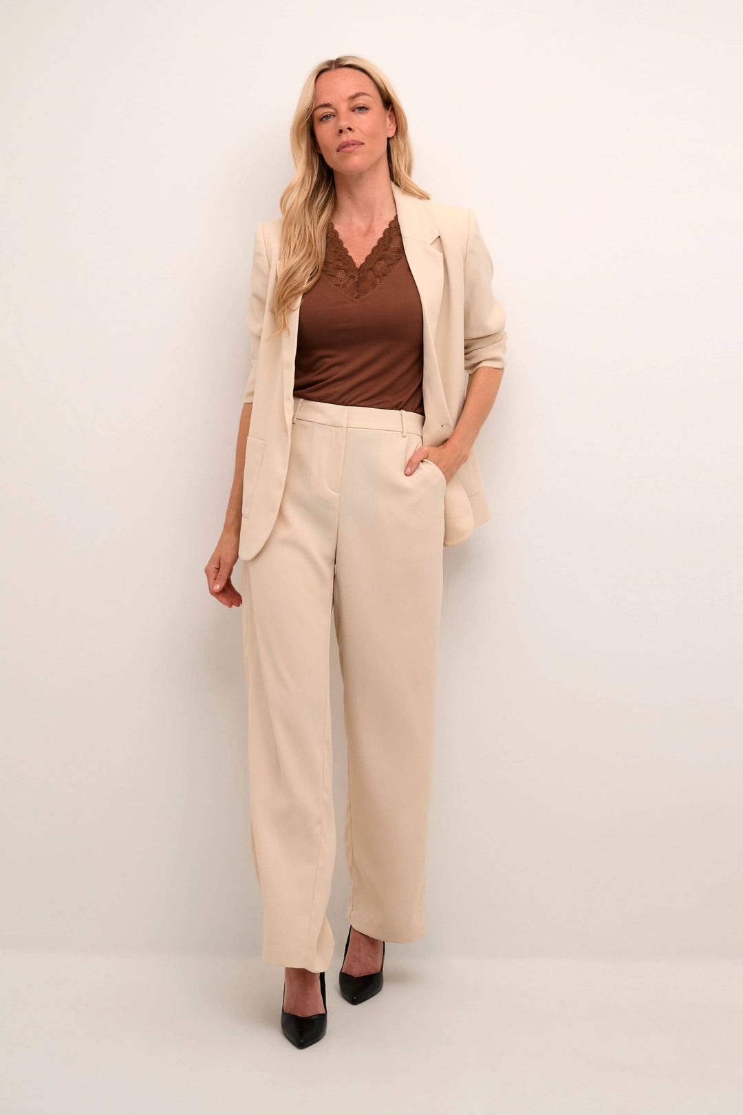 Femme professionnelle portant un veston Cocamia, haut marron et pantalon beige, parfait pour diverses occasions.