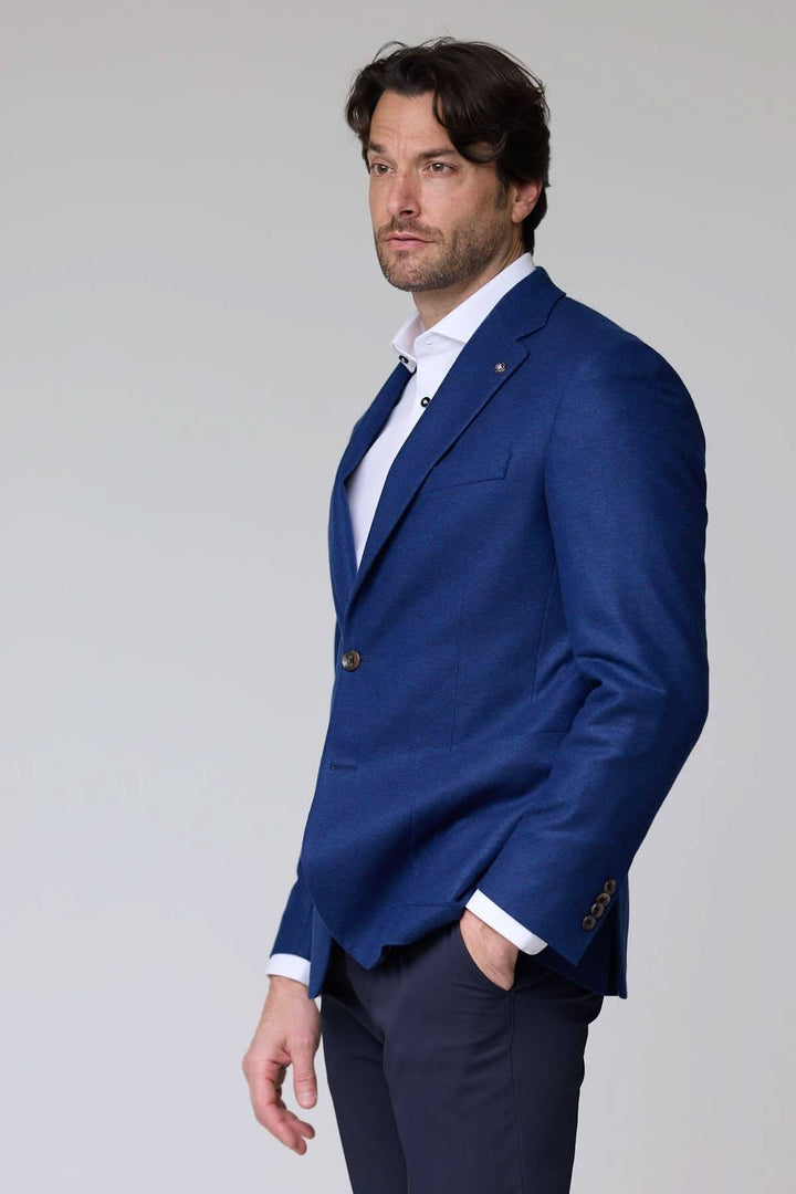 Veston DARWIN 100% Cachemire à deux boutons en bleu porté par un homme, élégant et moderne avec col à revers. Style professionnel raffiné.