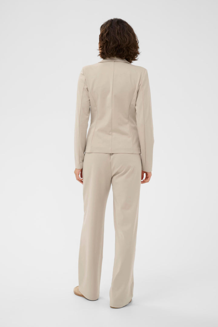 Vue arrière du Veston Jenny structuré, coupe ajustée, couleur beige, porté avec un pantalon assorti pour un look élégant et féminin.