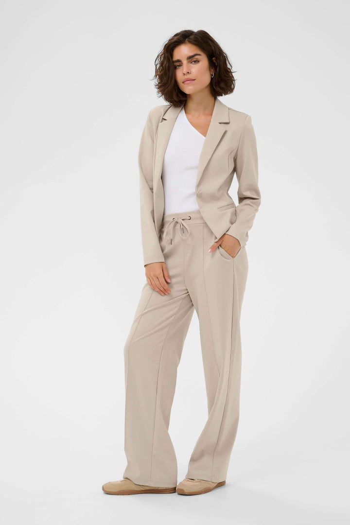 Femme portant le Veston Jenny structuré avec pantalon coordonné, offrant un look élégant et féminin au quotidien.