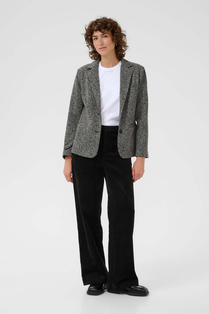 Veston Vineke avec coupe structurée, porté avec un t-shirt blanc et un pantalon noir, style chic décontracté.