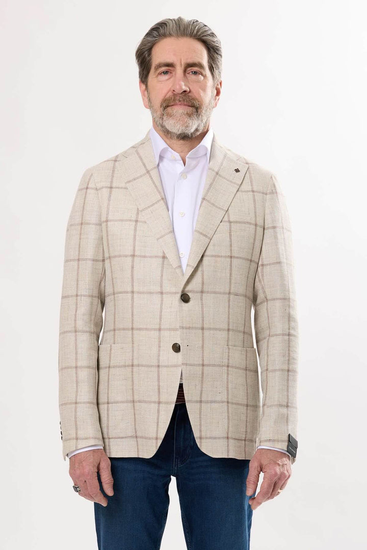 Homme portant un veston à carreaux, style décontracté, avec chemise blanche et jean foncé, élégant et contemporain.