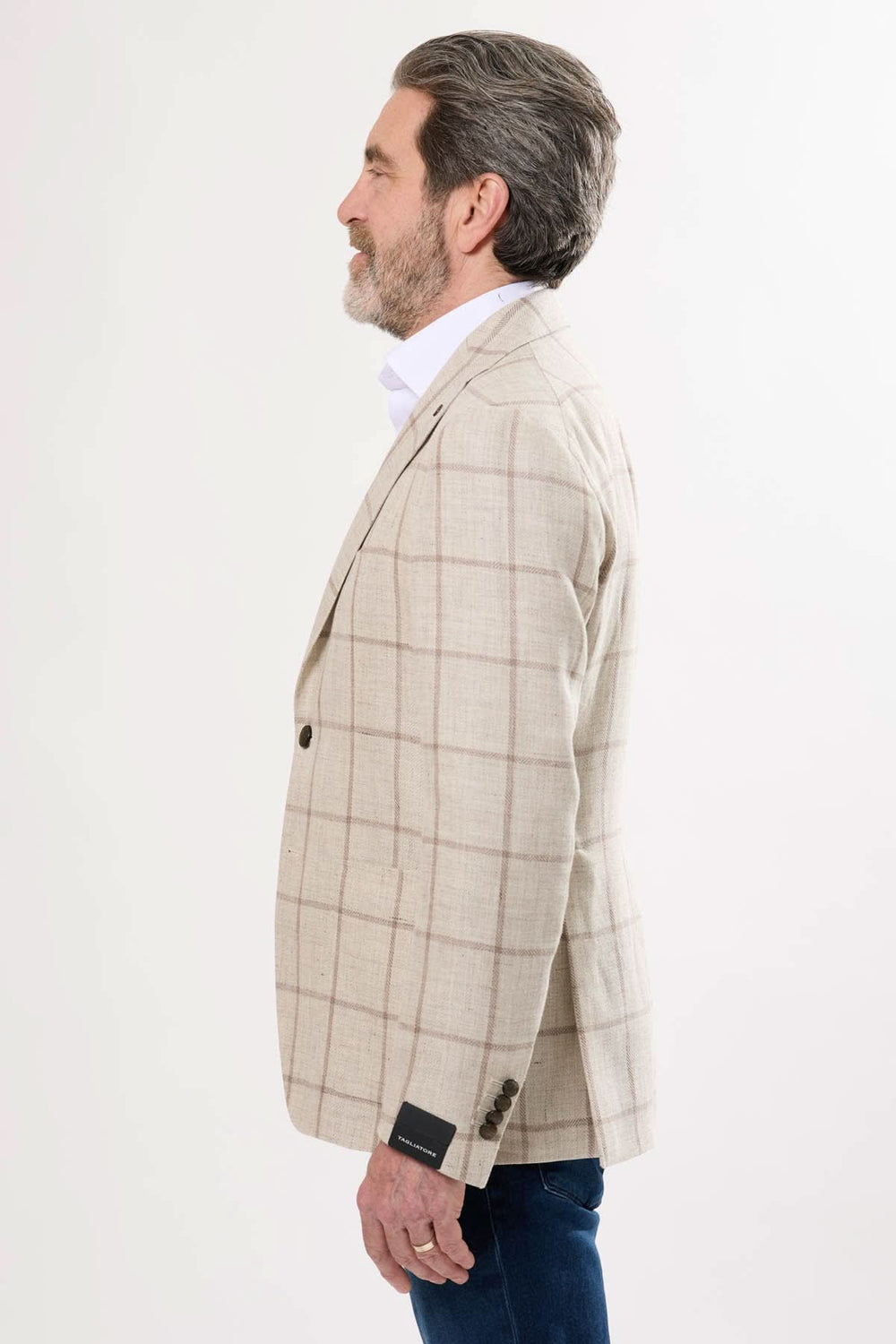 Homme en veston à carreaux couleur beige, vue de profil, style élégant et décontracté.