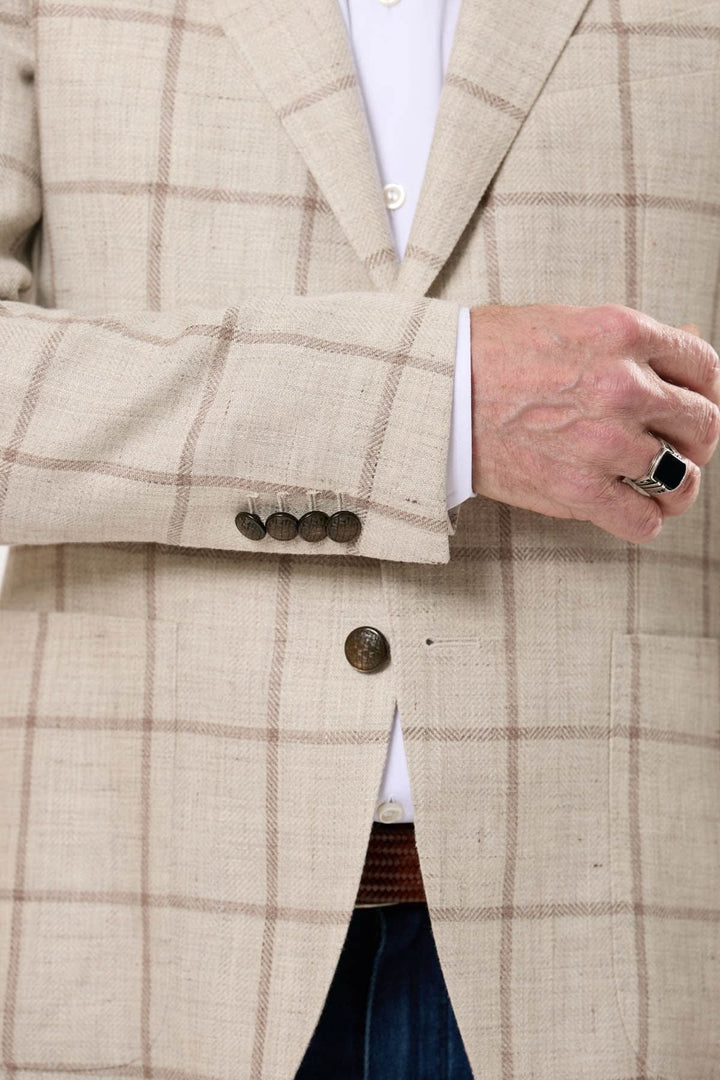 Veston à carreaux beige avec motif fenêtre, élégant et contemporain, porté par une personne avec une bague.