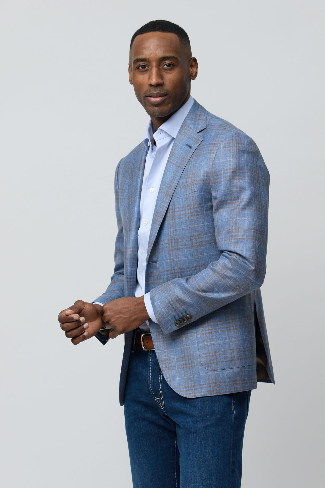 Homme portant un veston à carreaux en laine, soie et lin avec chemise bleue, style élégant et moderne.