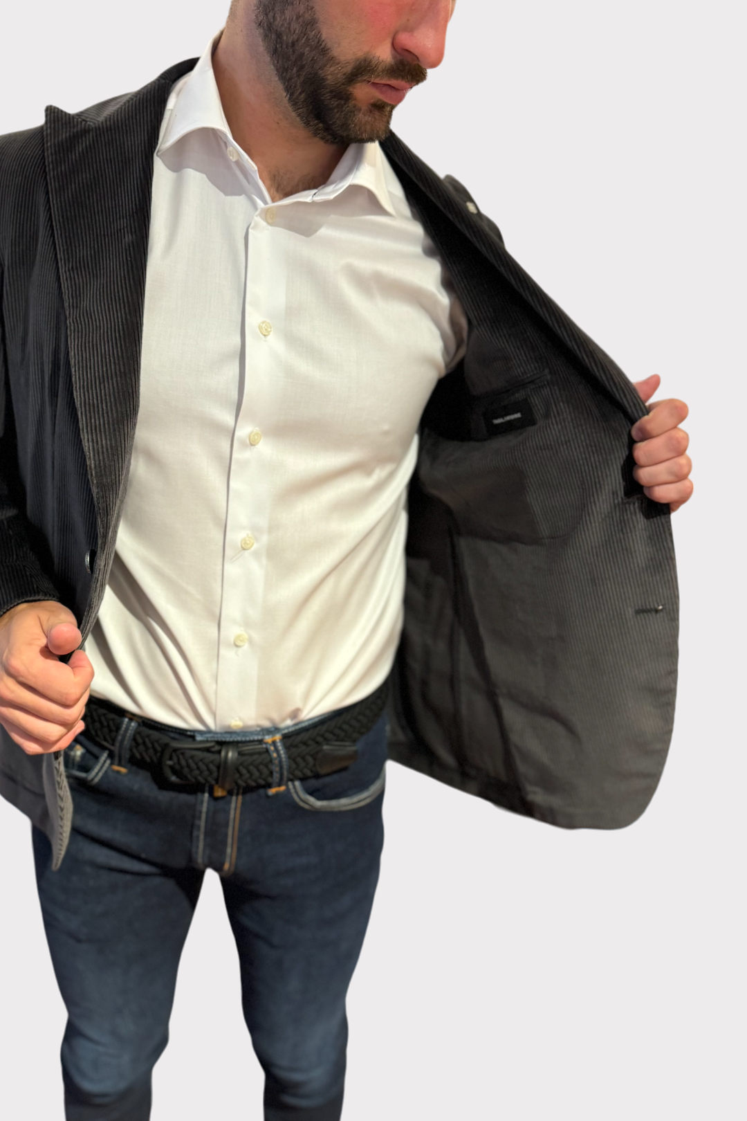 Veston en corduroy gris, intérieur élégant, porté avec une chemise blanche, look décontracté et moderne.