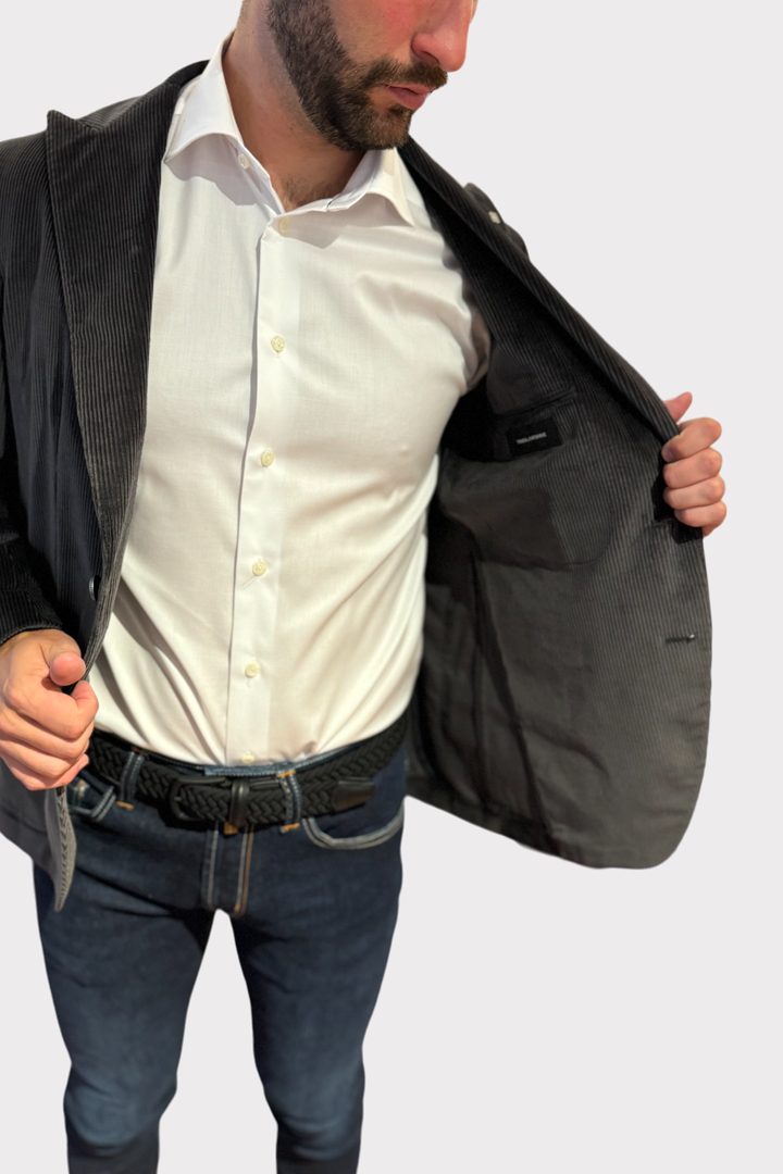 Veston en corduroy gris, intérieur élégant, porté avec une chemise blanche, look décontracté et moderne.