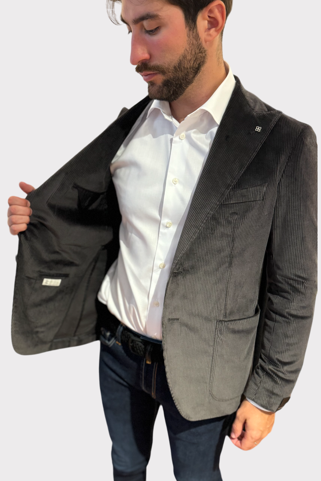 Blazer en velours côtelé gris porté par un homme, intérieur élégant avec une chemise blanche.