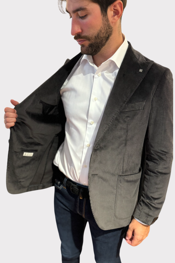 Blazer en velours côtelé gris porté par un homme, intérieur élégant avec une chemise blanche.