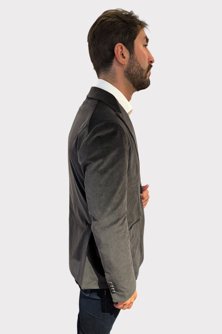 Blazer en velours côtelé gris porté de profil, alliant élégance et confort pour un look moderne.