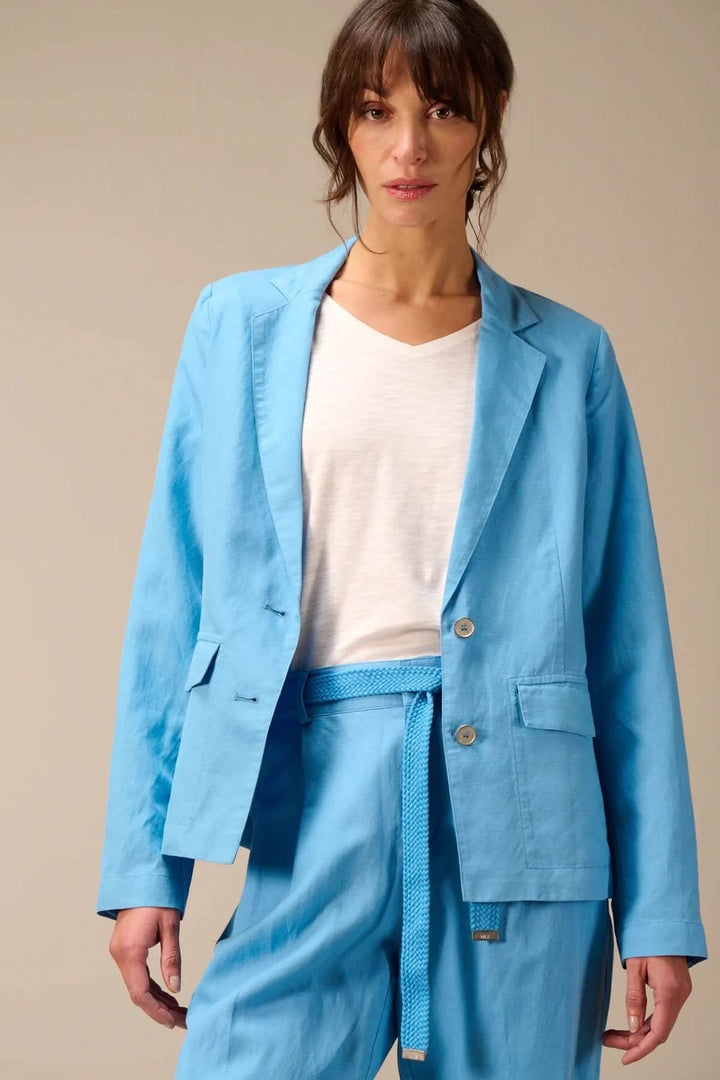 Femme portant un veston léger à coupe droite bleu avec col tailleur classique et fermeture boutonnée, manches longues.