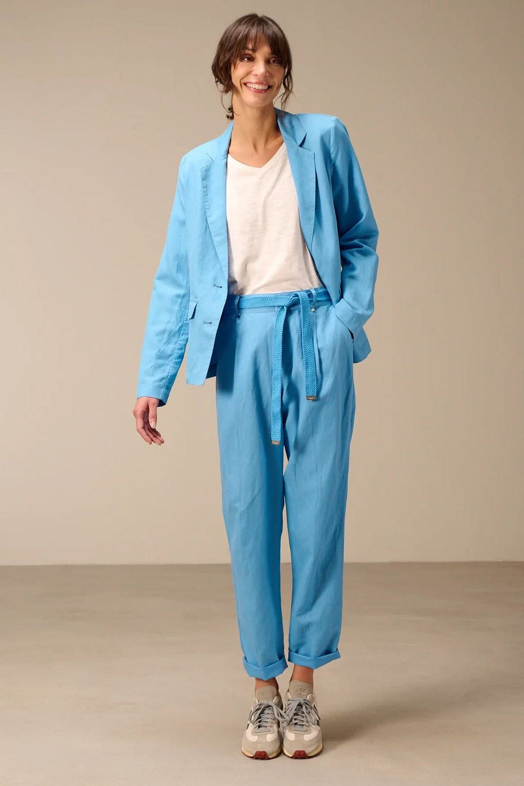 Veston léger à coupe droite bleu porté par une femme, mancherons longs et col tailleur. Style moderne et confortable.