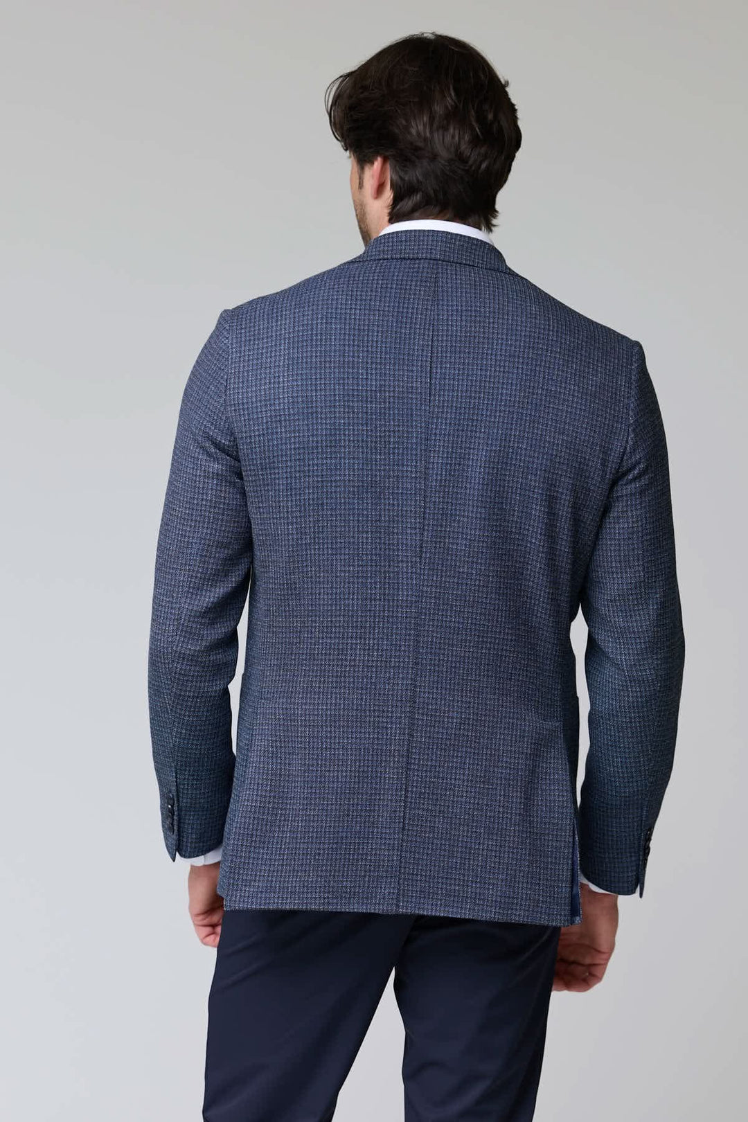 Homme portant un veston à motif texturé vu de dos avec fermeture à deux boutons et col à revers classique.
