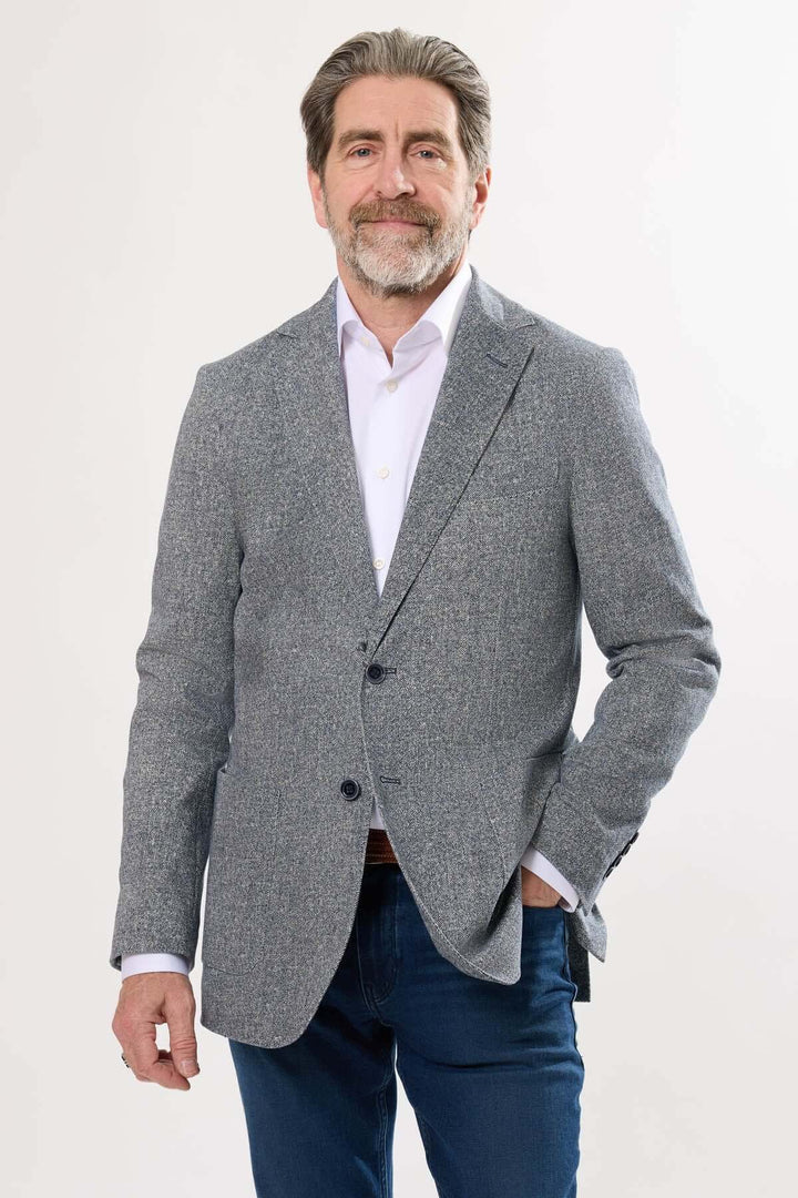 Homme portant un veston à texture subtile, élégant et décontracté, parfait pour les occasions estivales.