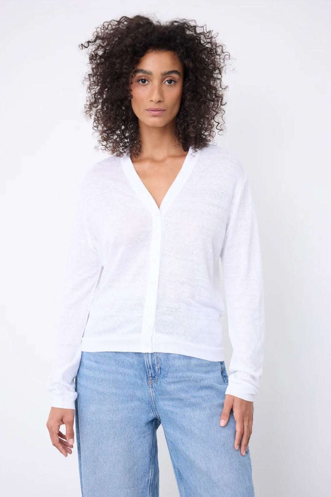 Femme portant un cardigan col v boutonné léger blanc avec un col en V, manches longues et coupe décontractée, sur fond blanc.