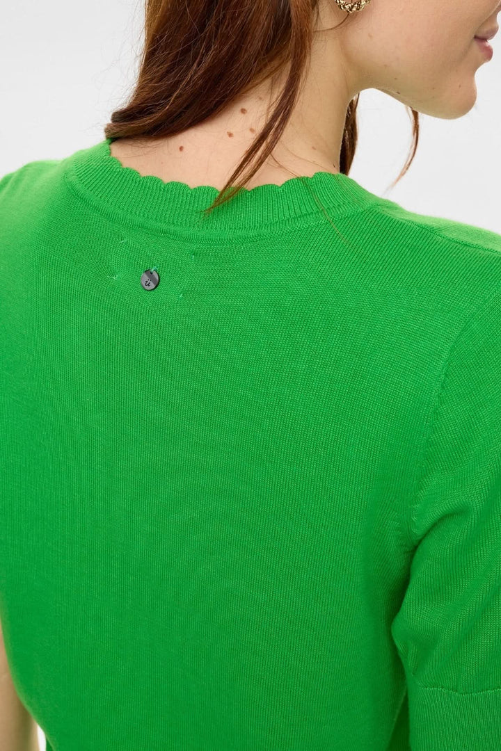 Détail du col festonné d'un chandail en tricot motif hibou vert vif"