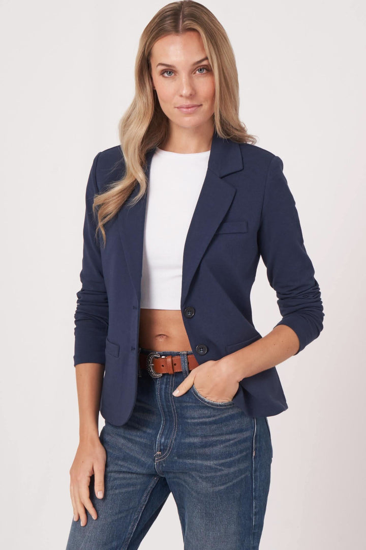 Veston en jersey stretch pour femme, confortable et chic, porté avec un top blanc et un pantalon en jean.